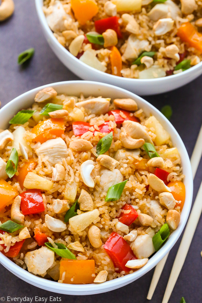 Easy Asian Rice Recipes for Dinner: Overhead view of two bowls of Pineapple Chicken Coconut Rice on a dark background.