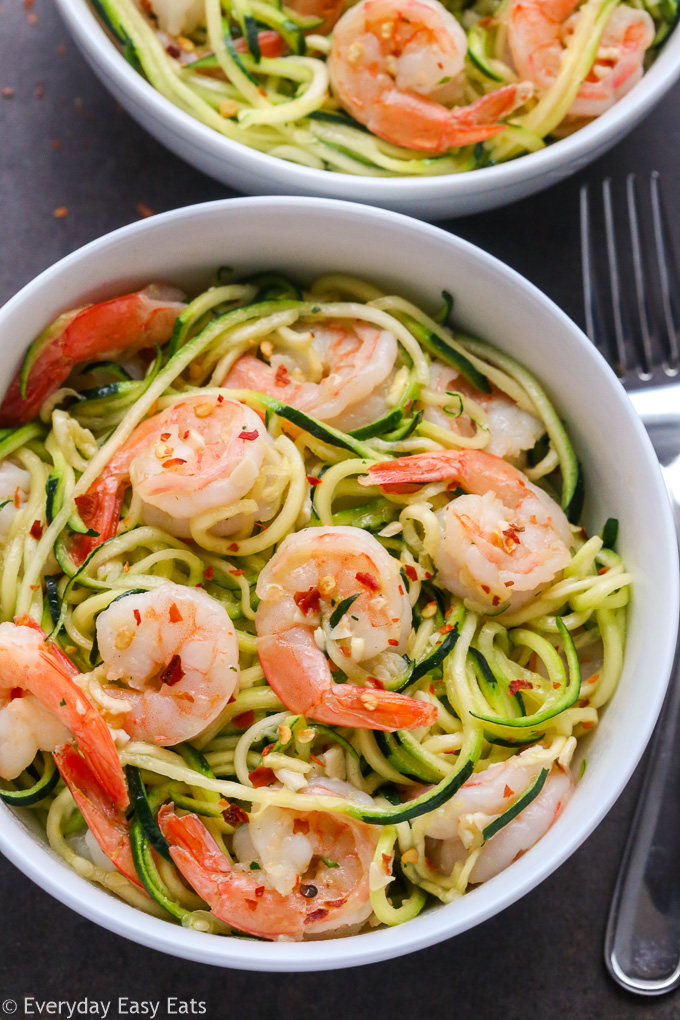 Healthy Meat Recipe: Close-up overhead view of Zucchini Noodles with Garlic Shrimp in white bowls on a black background.
