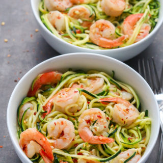 Overhead view of Garlic Shrimp Zucchini Noodles in white bowls on a black background.