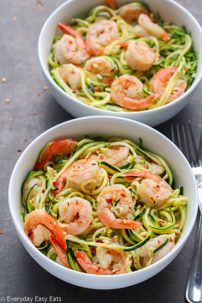 Overhead view of Garlic Shrimp Zucchini Noodles in white bowls on a black background.