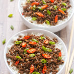 Overhead view of two bowls of Ground Beef Bulgogi with rice on a wooden surface with chopsticks on the side.