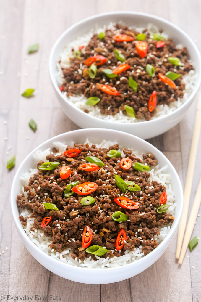 Overhead view of two bowls of Bulgogi Ground Beef with rice on a wooden surface with chopsticks on the side.