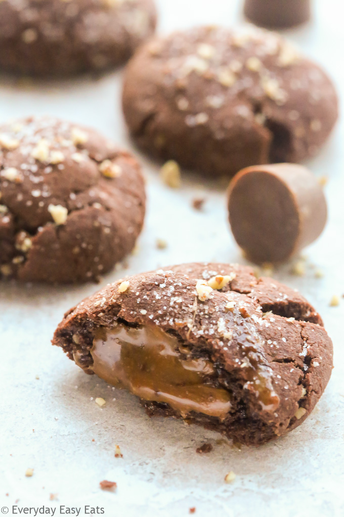 Close-up side view of Chocolate Rolo Cookies with scattered Rolo candies on a neutral background.