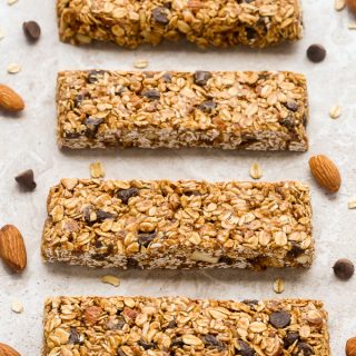 Overhead view of No-Bake Healthy Chocolate Chip Granola Bars on a neutral background with scattered almonds and chocolate chips.