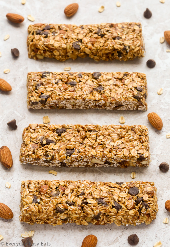 Overhead view of No-Bake Healthy Chocolate Chip Granola Bars on a neutral background with scattered almonds and chocolate chips.