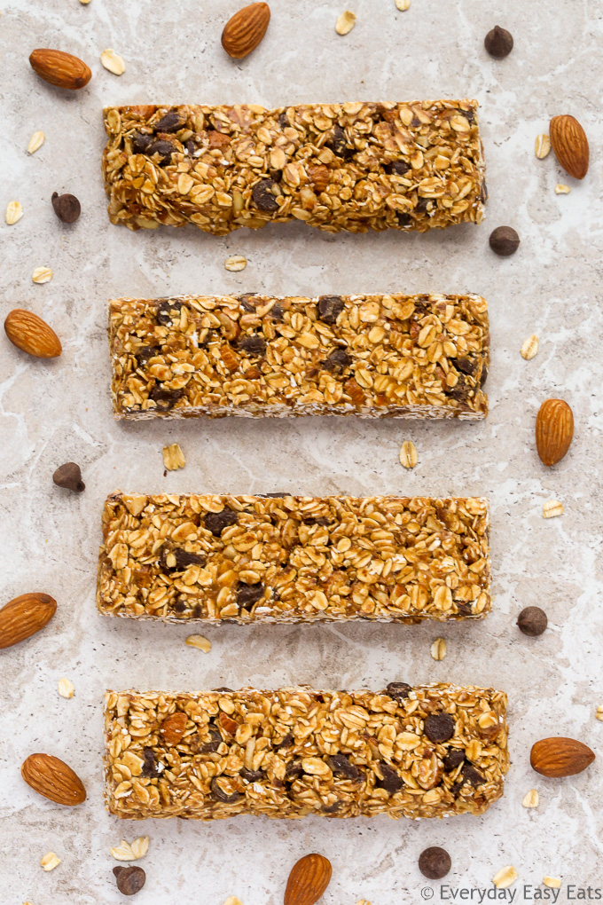 Overhead view of Chocolate Chip Granola Bars on a neutral background with scattered almonds and chocolate chips.