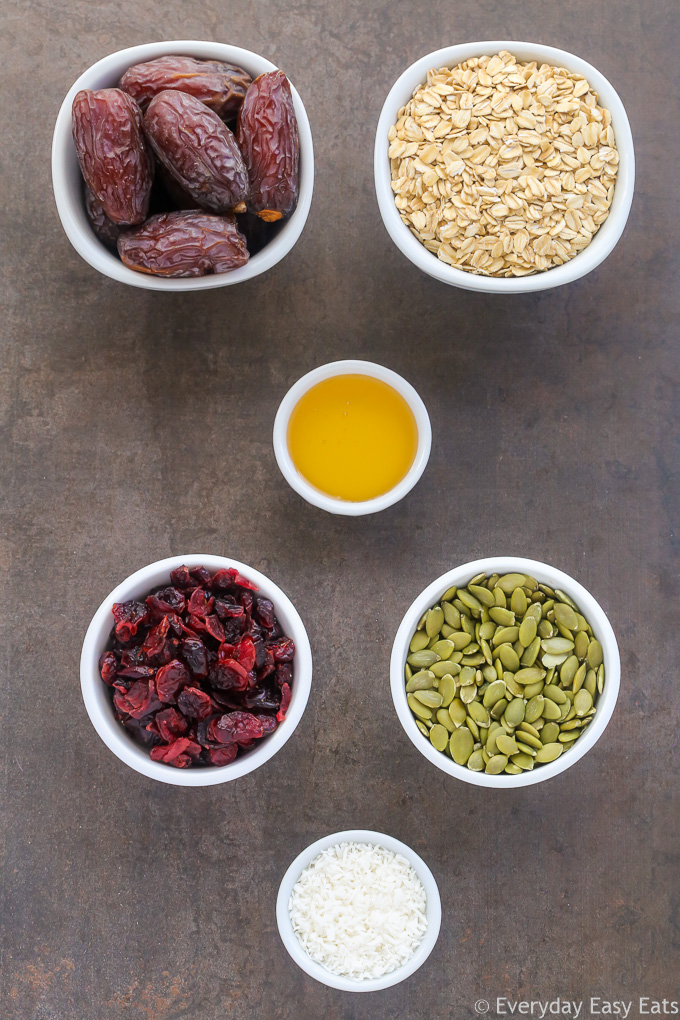 Overhead view of Healthy No-Bake Nut-Free Granola Bars ingredients in white bowls on a dark background.