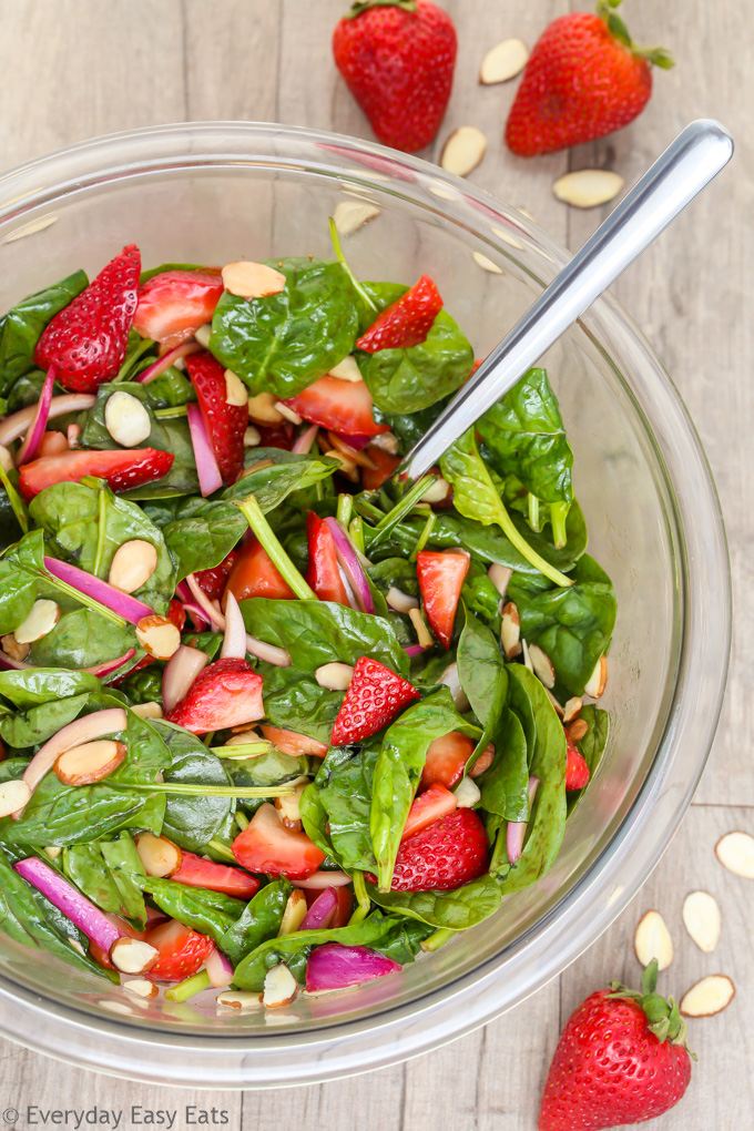 Strawberry Spinach Salad with Balsamic Dressing in a glass serving bowl on a wooden background