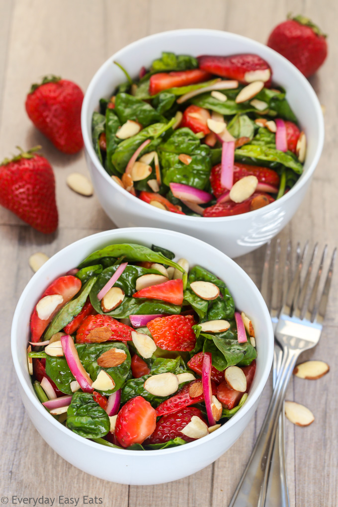 Two bowls of Strawberry Spinach Salad with Balsamic Dressing on a wooden background