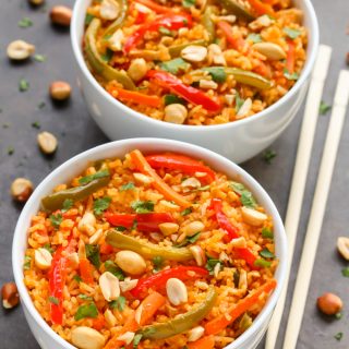 Two bowls of Thai Red Curry Rice with chopsticks, scattered peanuts, and cilantro on a dark background.