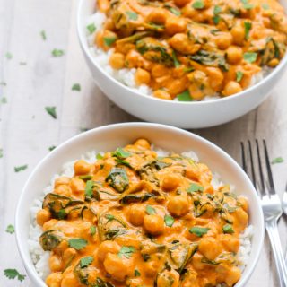 Overhead view of two bowls of Indian Coconut Chickpea Curry with white rice on a wooden background.