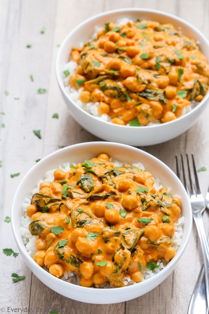 Overhead view of two bowls of Indian Coconut Chickpea Curry with white rice on a wooden background.