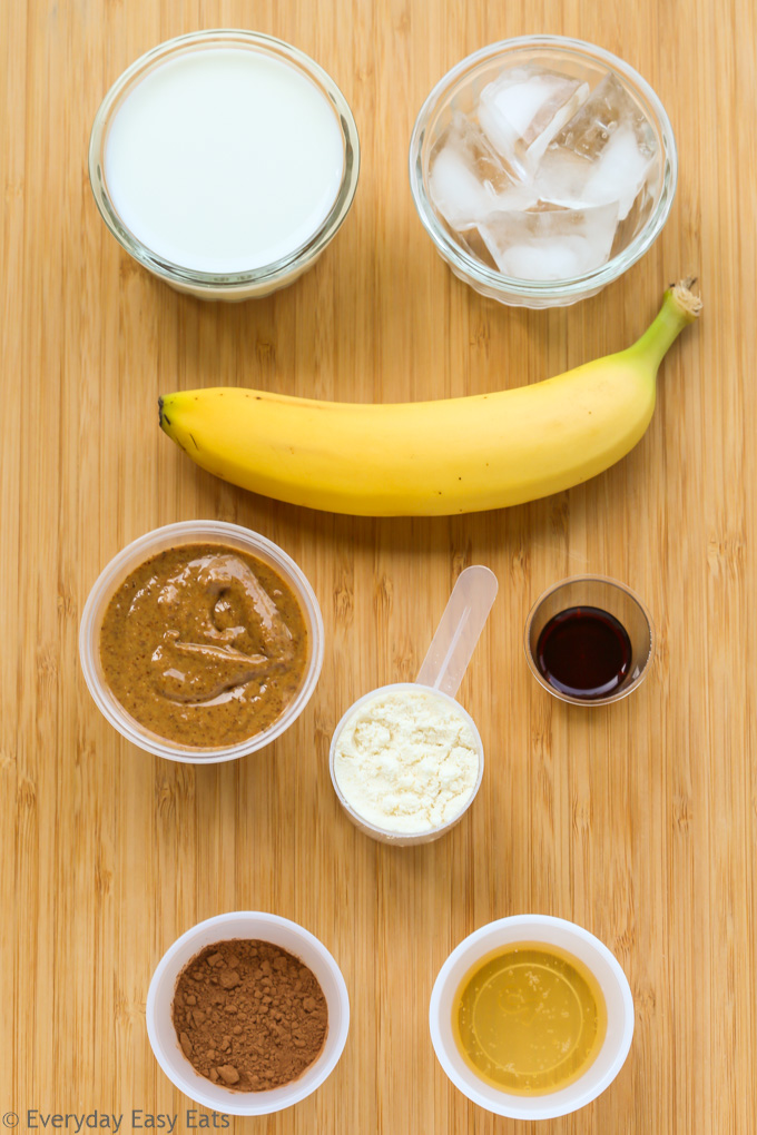 Overhead view of ingredients for Chocolate Peanut Butter Protein Shake on a wooden background.