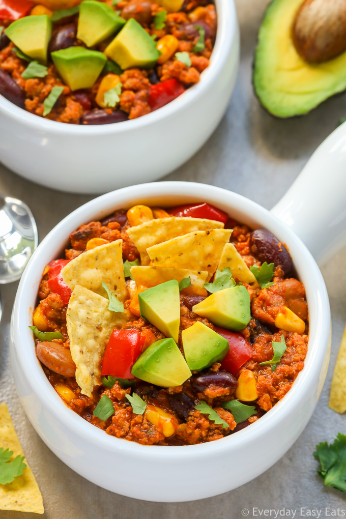 Close-up overhead view of a bowl of Ground Turkey Chili on a beige background.