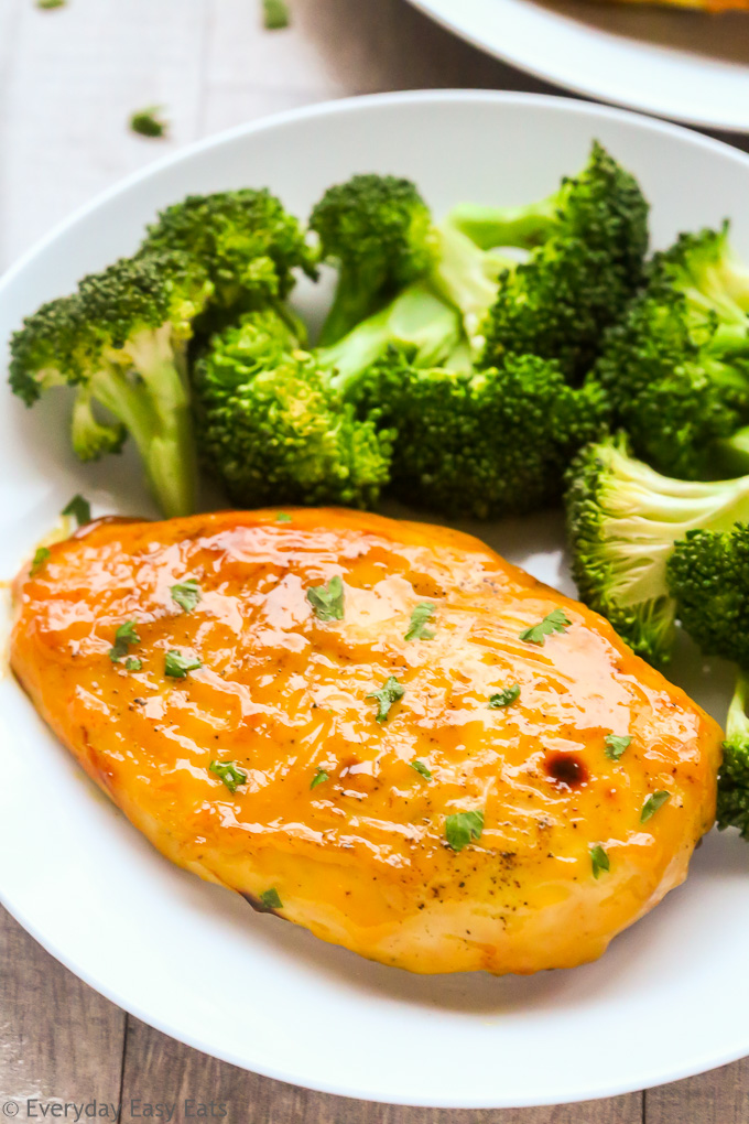 Close-up overhead view of Baked Honey Mustard Chicken Breasts in a white plate with steamed broccoli.