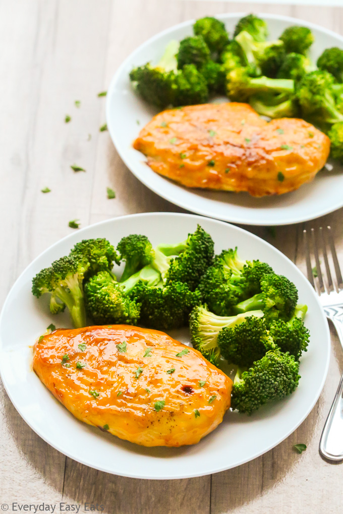 Overhead view of two plates of Baked Honey Mustard Chicken Breasts with steamed broccoli.