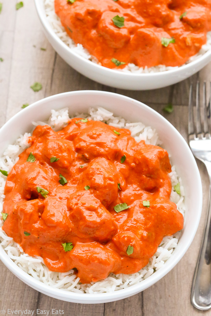 Close-up overhead view of a bowl of Easy Butter Chicken with white rice on a wooden background.
