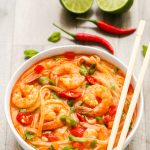 Side overhead view of Thai Shrimp Soup with Noodles in a white bowl with chopsticks on a wooden background.