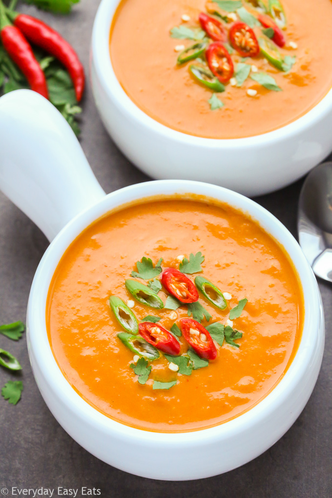 Close-up overhead view of Spicy Thai Pumpkin Soup in white bowls on black background.