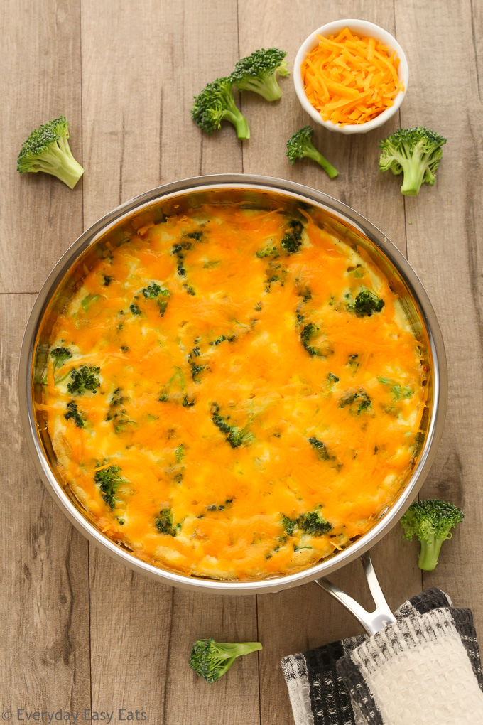 Overhead view of Broccoli Cheese Frittata in a skillet on a wooden background.