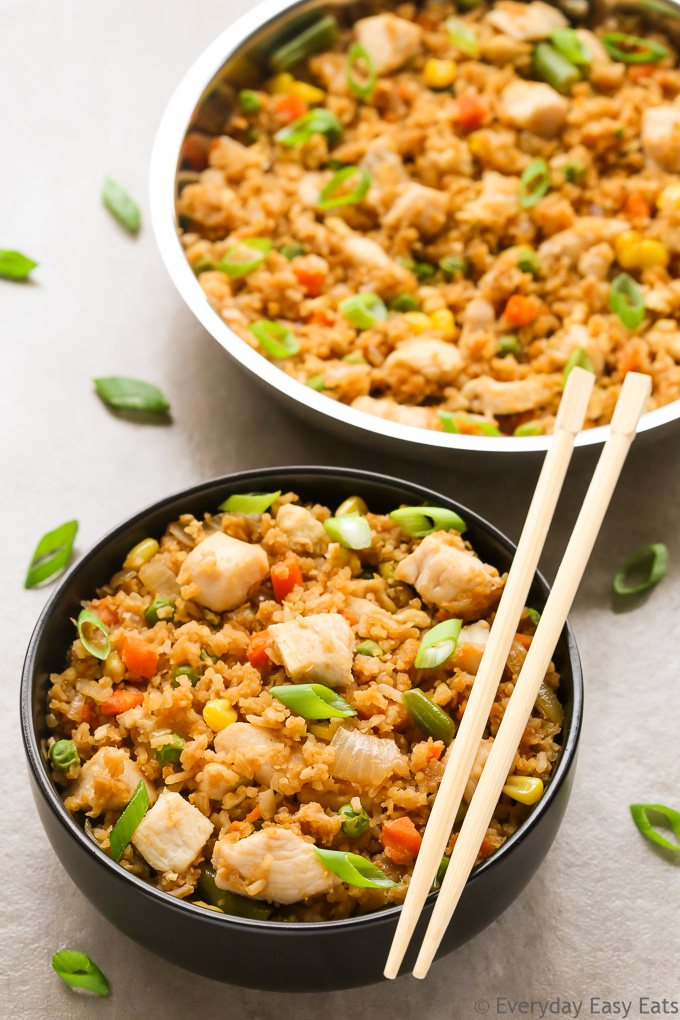 Overhead view of a bowl of Healthy Chicken Fried Rice with chopsticks on the side on a neutral background.