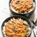 Overhead view of two bowls of Coconut Lentil Curry with spoons on the side on a neutral background.