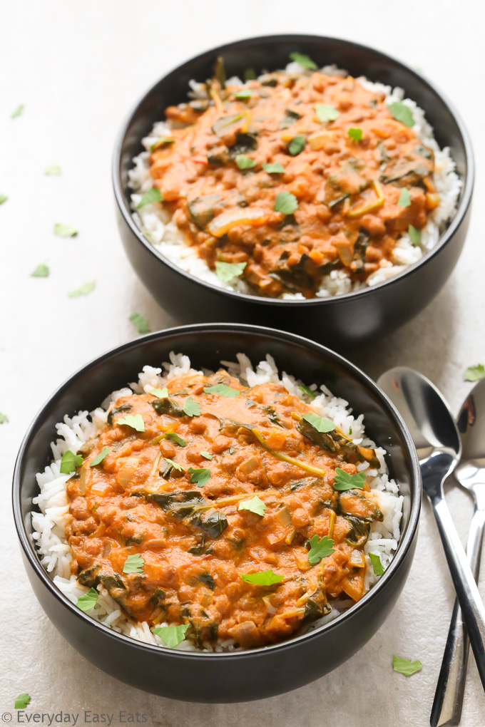 Overhead view of two bowls of Coconut Lentil Curry with spoons on the side on a neutral background.