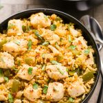 Close-up overhead view of a bowl of Cajun Chicken and Rice on a beige background.