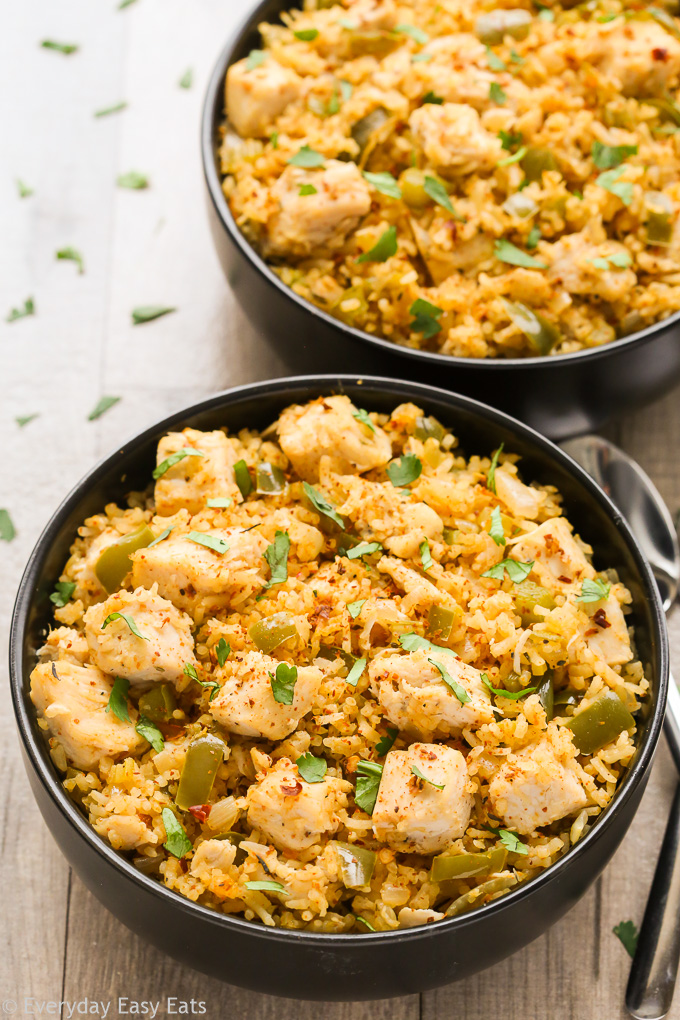 Close-up overhead view of two bowls of Cajun Chicken and Rice on a beige background.