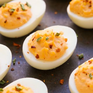 Close-up overhead view of spicy deviled eggs on a dark background.