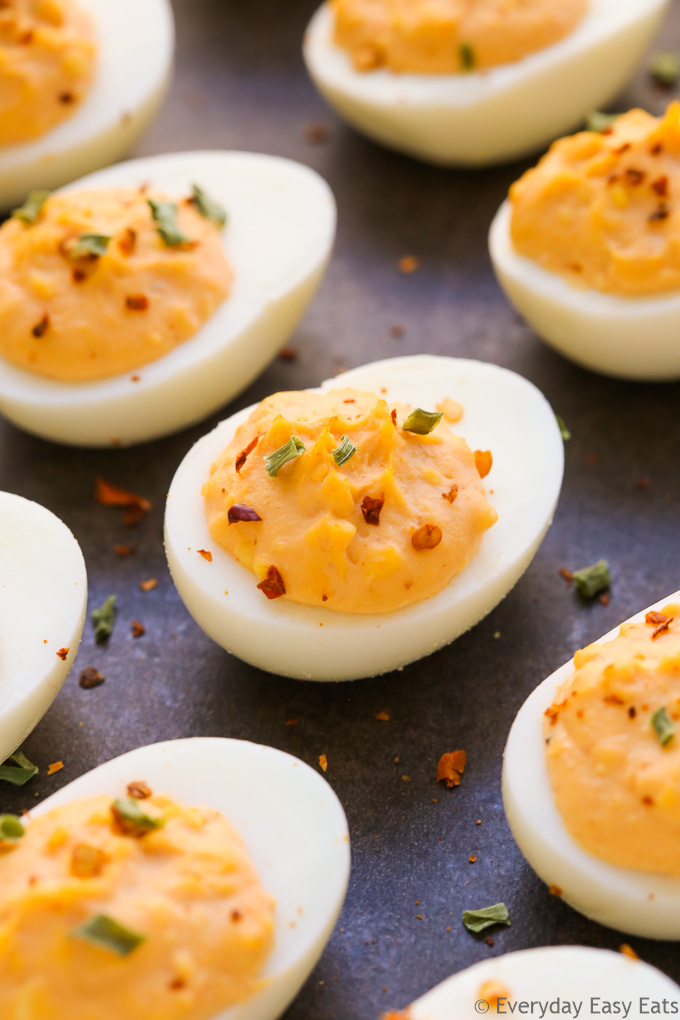 Close-up overhead view of spicy deviled eggs on a dark background.