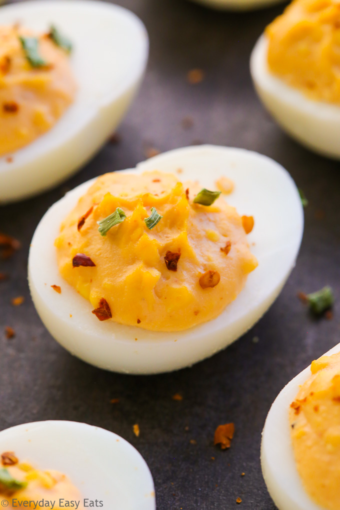 Very close-up overhead view of spicy deviled eggs on a dark background.