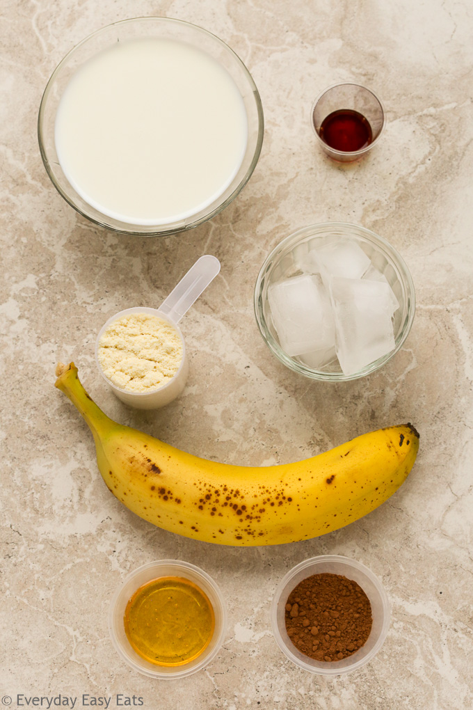 Overhead view of ingredients required to make Chocolate Protein Shake on a neutral background.