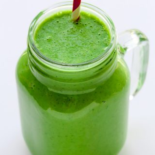 Overhead view of a Green Protein Shake in a glass with a straw on a white background.