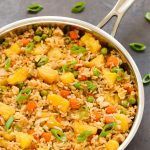 Close-up overhead view of a skillet of Pineapple Fried Rice on a dark background.