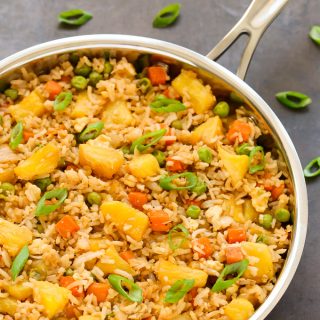 Close-up overhead view of a skillet of Pineapple Fried Rice on a dark background.