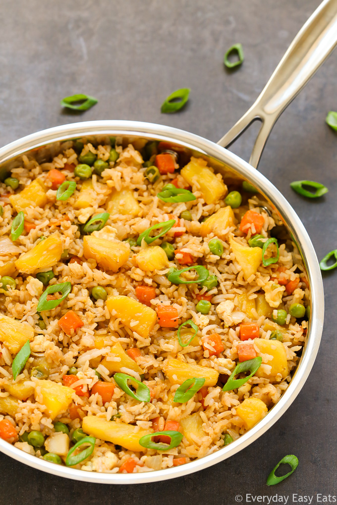 Close-up overhead view of a skillet of Easy Pineapple Fried Rice on a dark background.