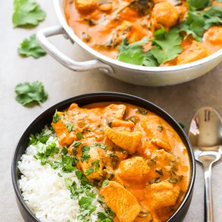 Overhead view of Indian Coconut Chicken Curry with white rice in a bowl with a spoon on the side.