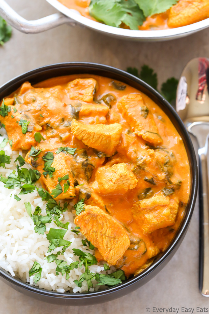 Close-up overhead view of Indian Coconut Chicken Curry with white rice in a bowl with a spoon on the side.