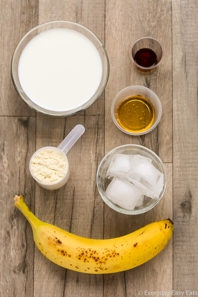 Overhead view of ingredients required to make Vanilla Protein Shake on a wooden background.
