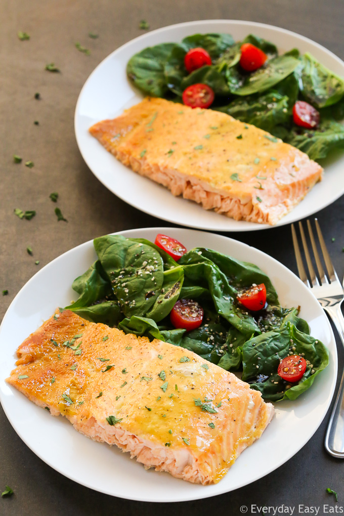Healthy Meat Recipe: Side overhead view of two pieces of Healthy Baked Honey Mustard Salmon in white plates with salad on the side.
