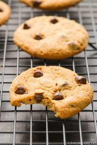 Close-up side view of a Peanut Butter Chocolate Chip Cookie with a bite taken out of it on wire cooling rack.