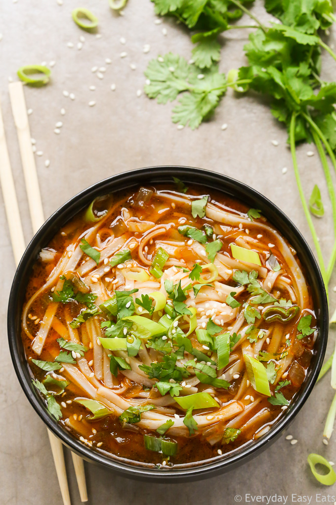 Overhead view of Spicy Asian Noodle Soup in a black bowl on a neutral background.