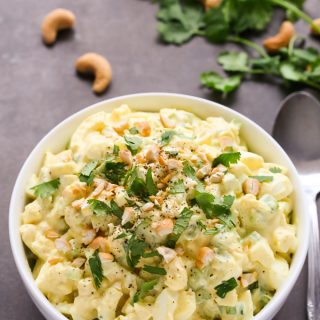 Overhead view of Curried Egg Salad in a white bowl on a black surface.