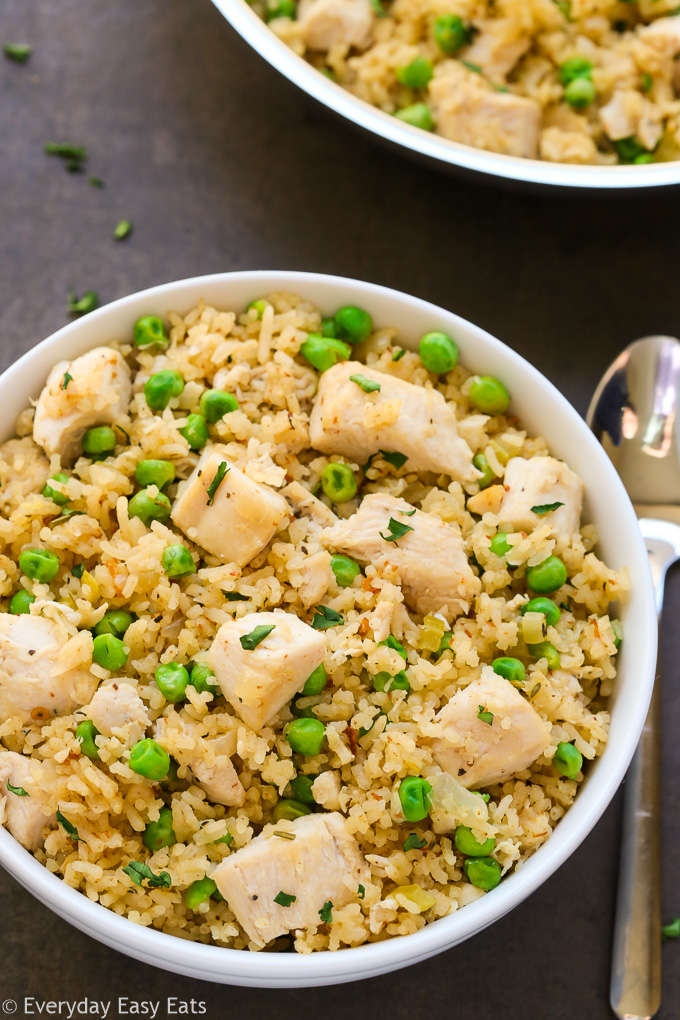 Close-up overhead view of One-Pot Chicken and Rice in a white bowl with a spoon on the side.