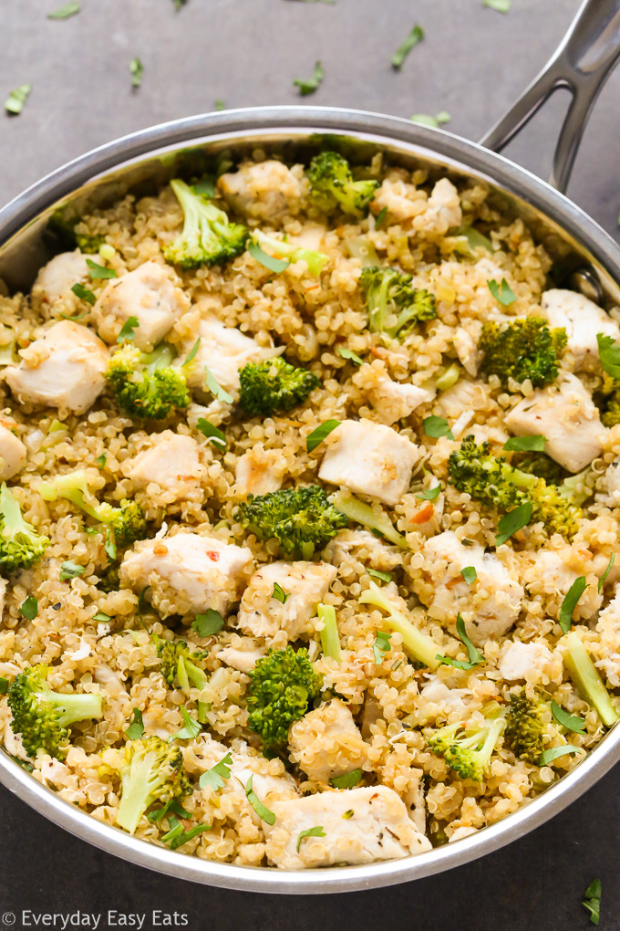 Close-up overhead view of Chicken Broccoli Quinoa in a silver skillet on a black surface.