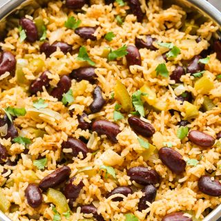 Close-up overhead view of Vegetarian Dirty Rice in a silver skillet on a dark surface.