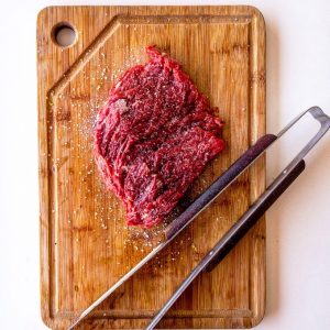 Is It Safe to Order Meat Online: Overhead view of beef on a wooden chopping board.