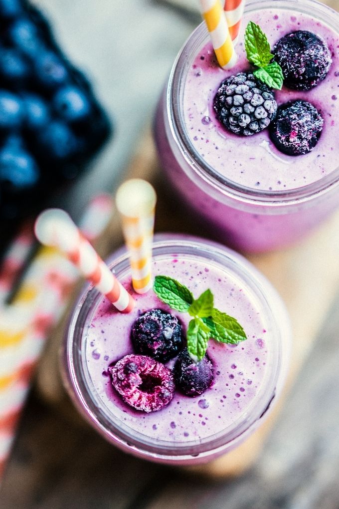 Close-up overhead view of Mixed Berry Protein Shakes in glass jars with straws.