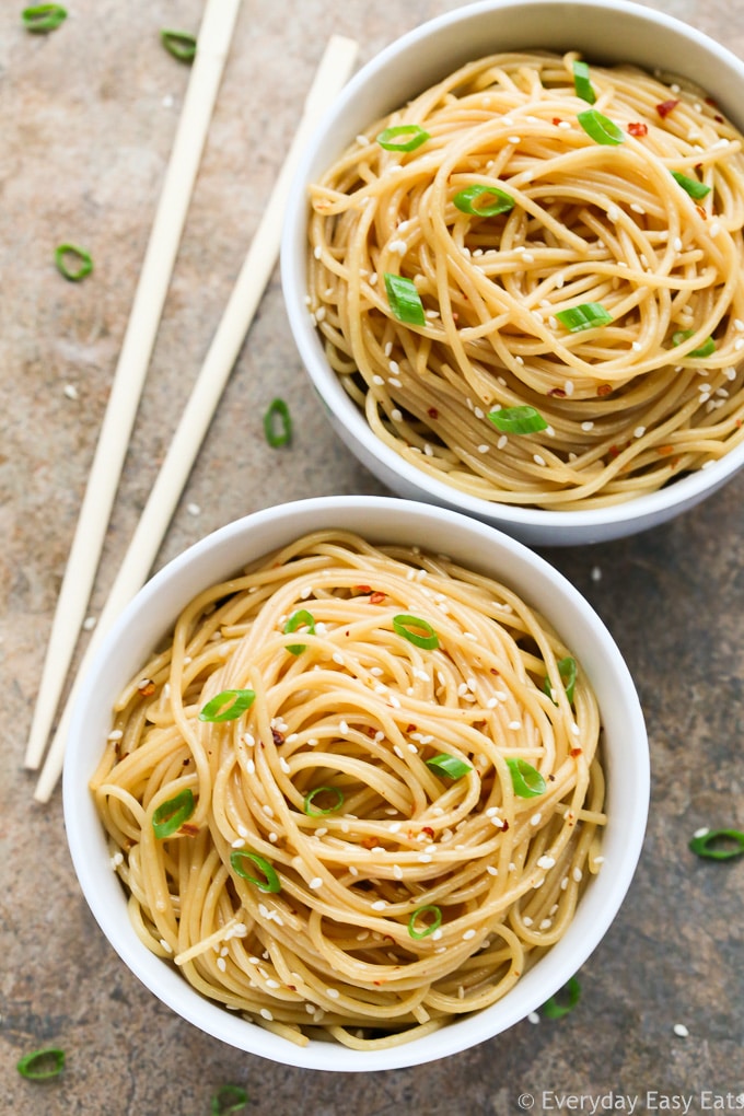 This Easy Sesame Noodles recipe is tastes even better than takeout. Ready to eat in just 15 minutes! | EverydayEasyEats.com Overhead view of two bowls of Chinese Sesame Noodles with chopsticks on the side on a neutral background.
